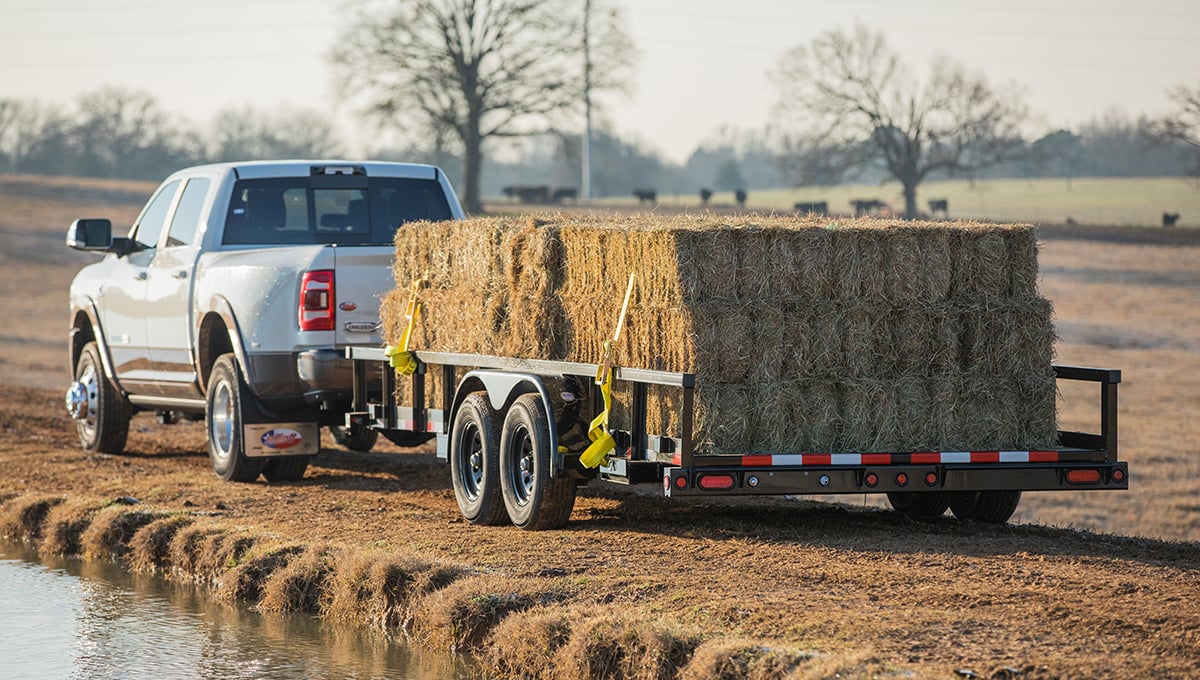 a white truck is pulling a 10pi trailer full of hay