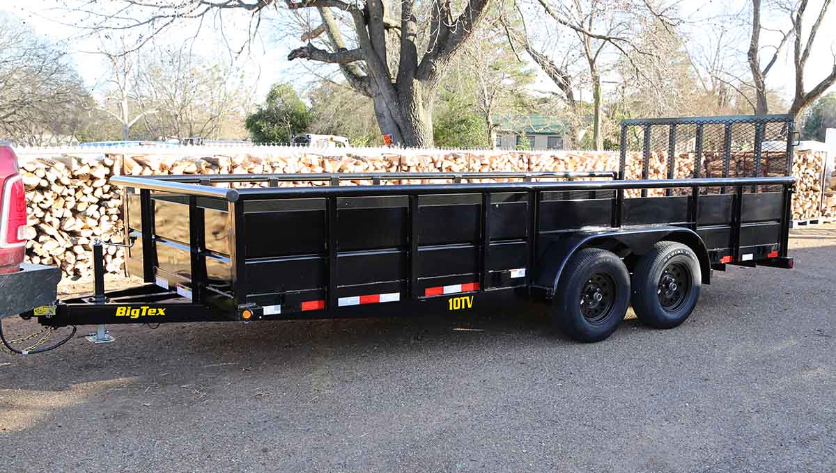 a 10tv big tex trailer is parked in front of a pile of logs