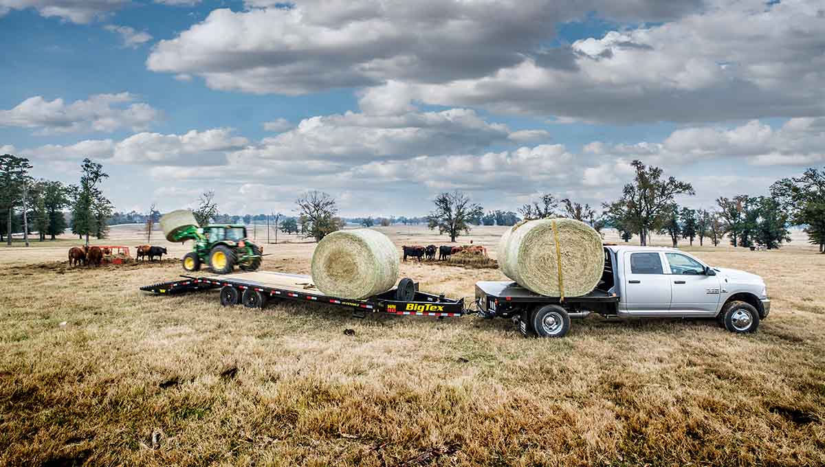a ram truck is towing a 14ph gooseneck trailer with bales of hay on it