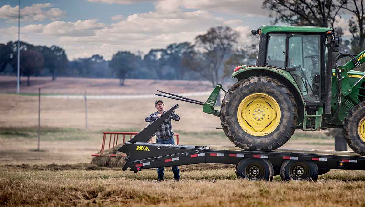 a john deere tractor is on a 14ph gooseneck trailer in a field