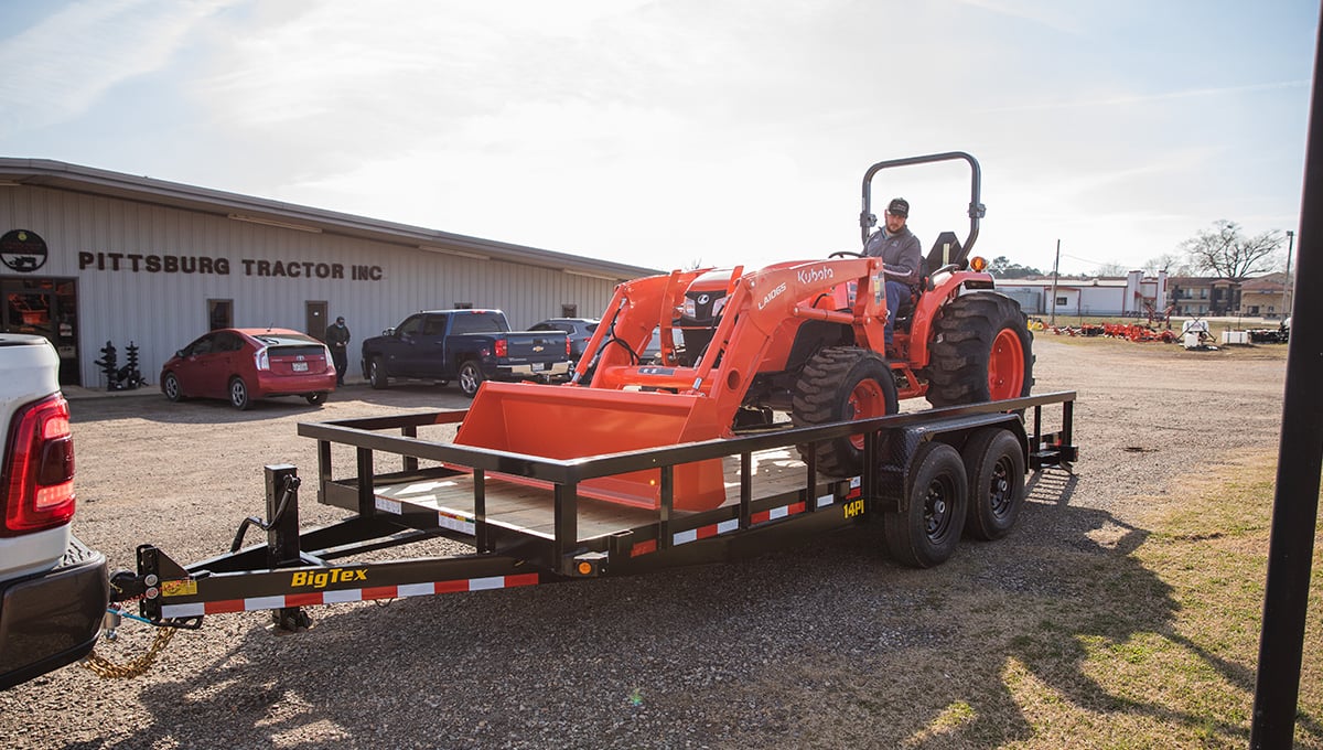 a man is driving a kubota tractor on a trailer