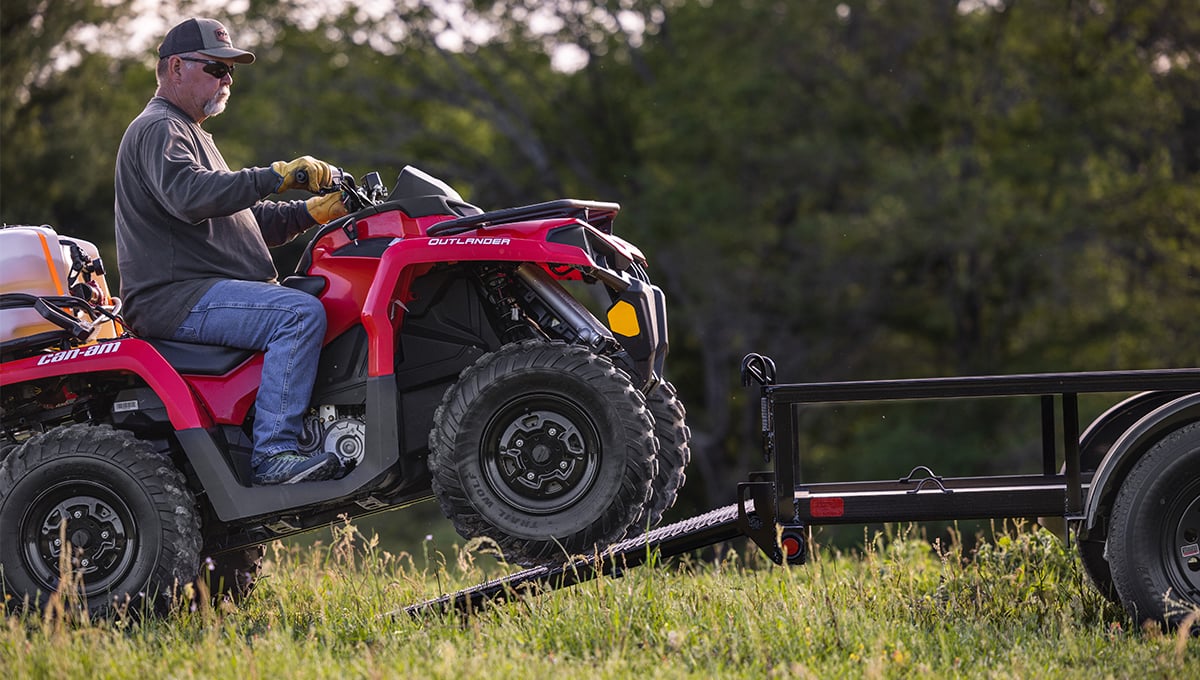 a man is driving a red can-am outlander atv