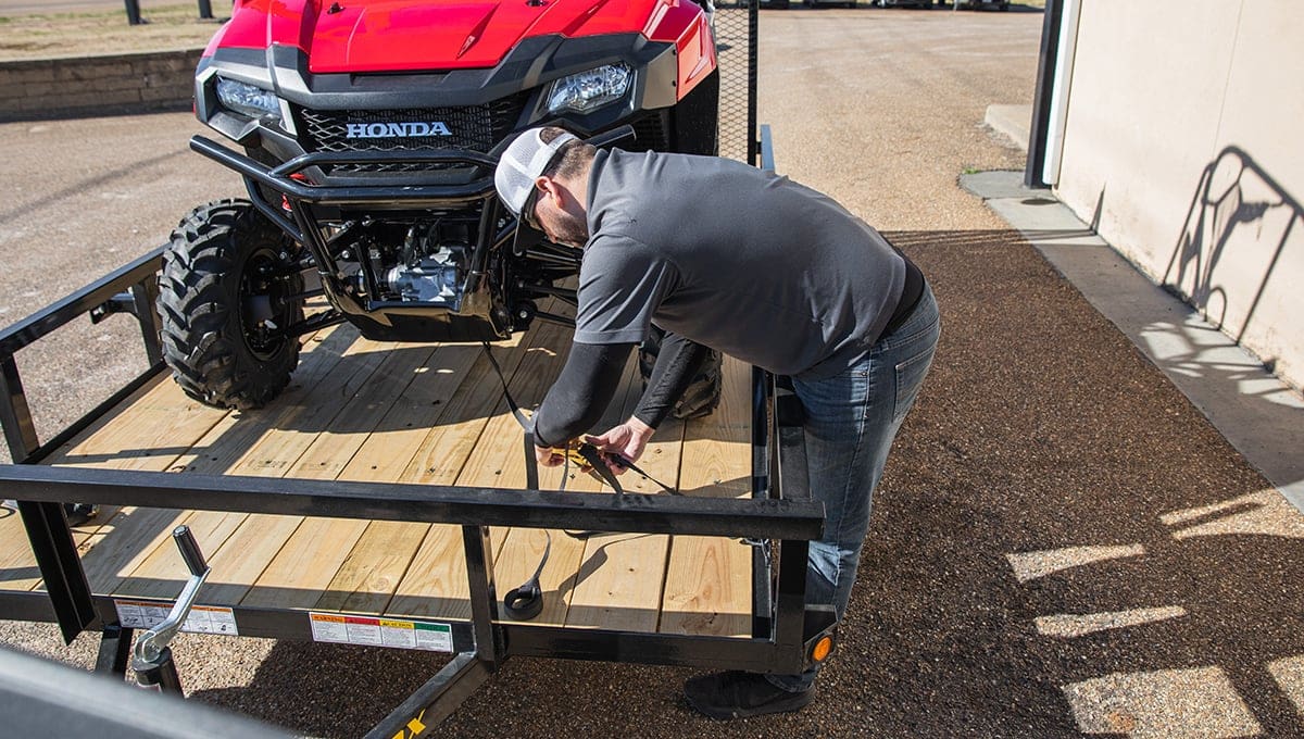 a man is working on a honda atv on a 35sa utility trailer