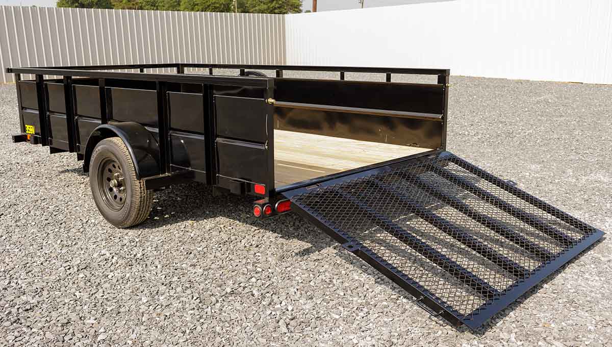 a black trailer with a ramp is parked on gravel