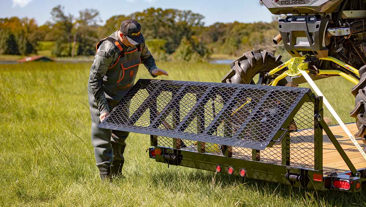 a man is loading a polaris motorcycle on a 35ut atv trailer