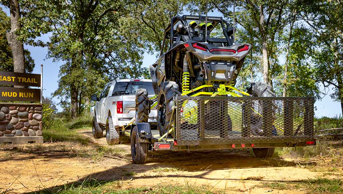 a white truck is towing a 35UT ATV hauler on a trailer