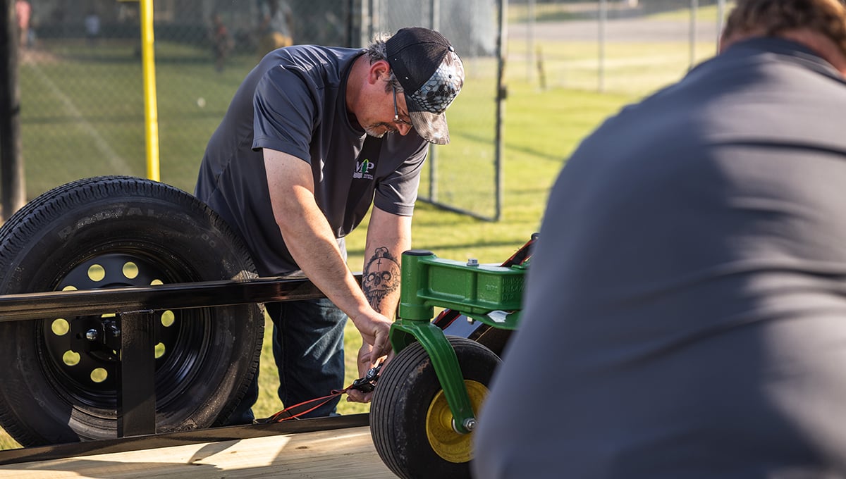 a man with a tattoo on his arm is working on a john deere trailer