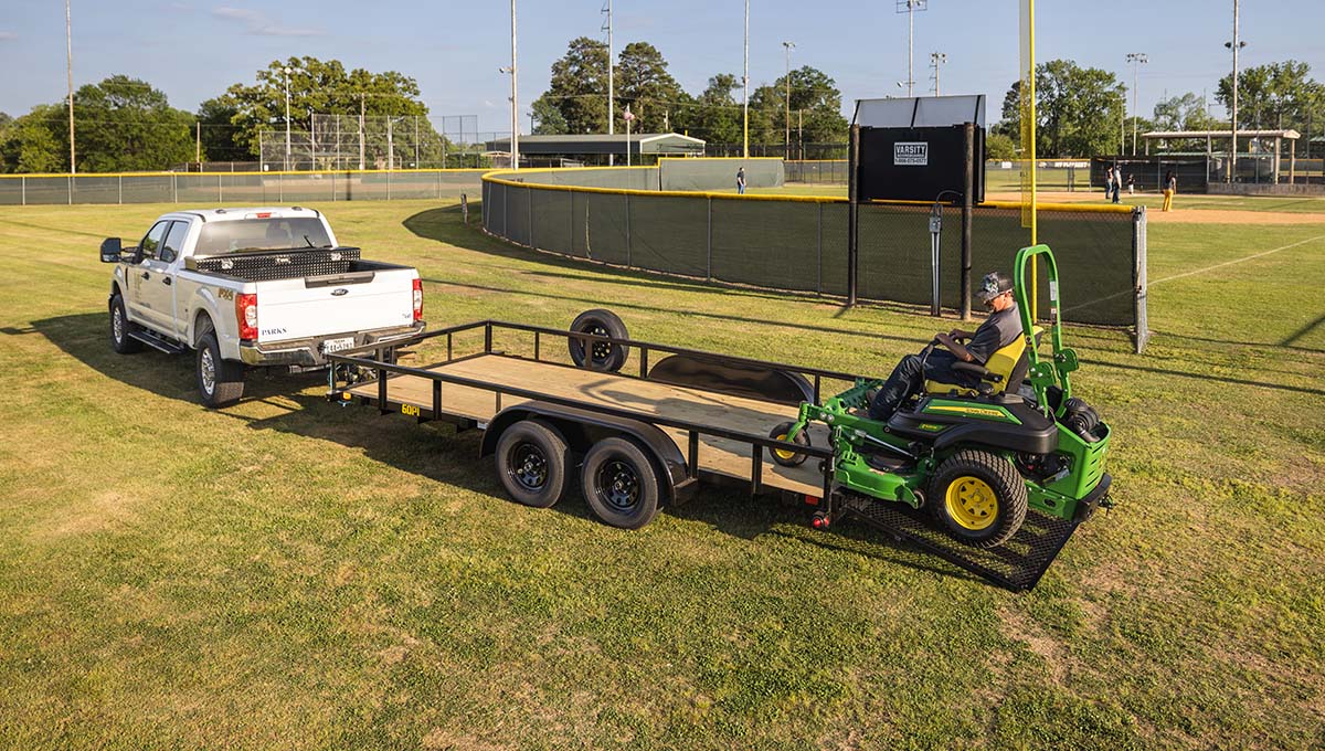 a man is driving a john deere lawn mower on a 60pi trailer