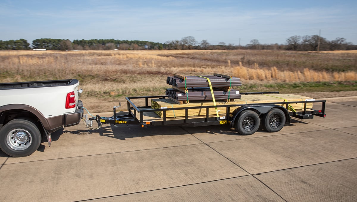 a ram truck is towing a 70pi utility trailer with a stack of wood on it
