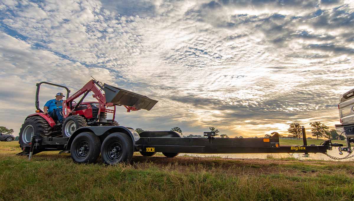 a tractor is being towed by a big tex 10ch trailer