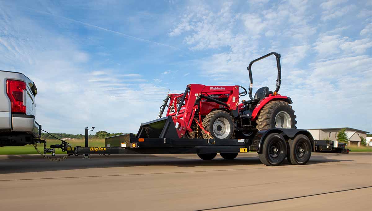 a mahindra tractor is being towed by a 10ch car hauler