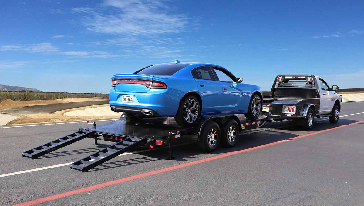 a blue dodge charger is being towed by a 10dm car hauler