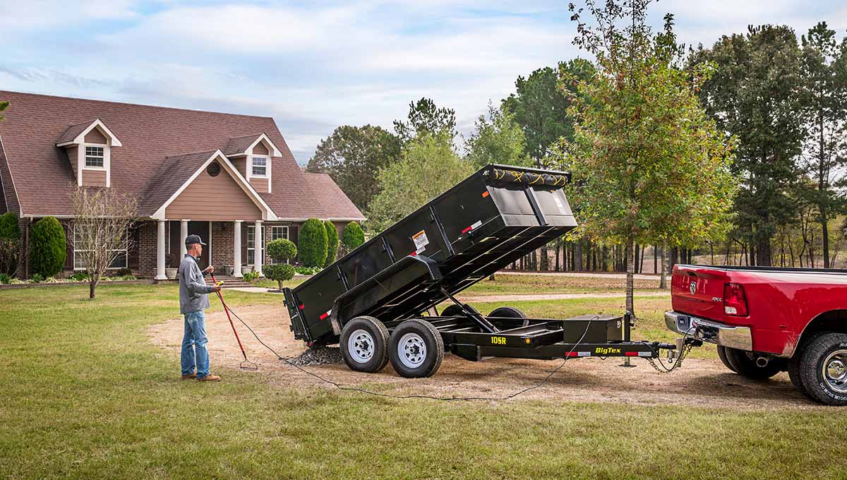 a man is loading a 10sr dump trailer into a red truck