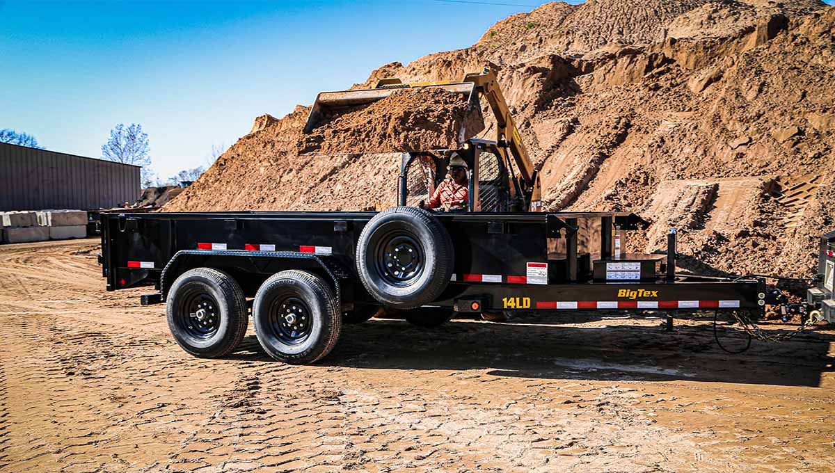 a large pile of dirt is behind a big tex 14ld dump trailer