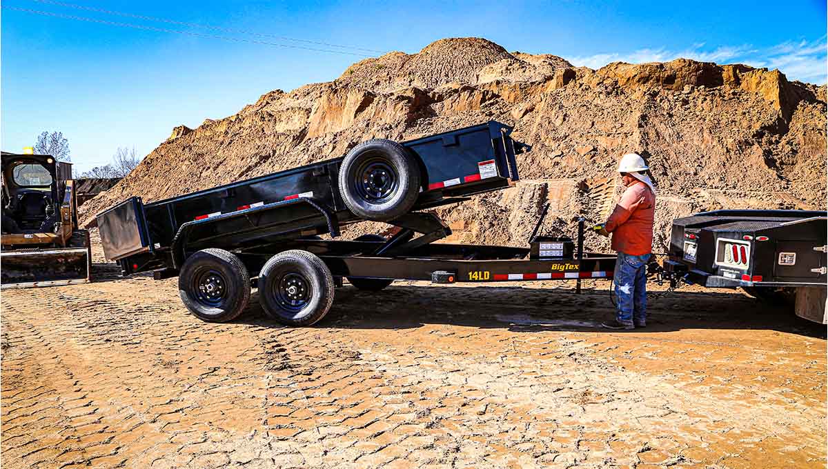 a man standing next to a 14ld commercial grade dump trailer that says big tex