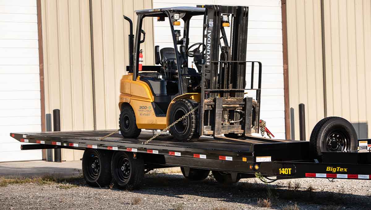 a forklift is sitting on top of a 140t big tex trailer