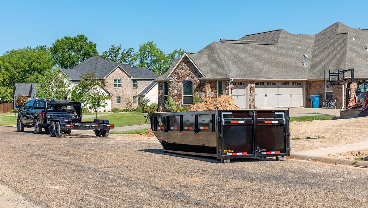 a 14rd roll off dump trailer is sitting in front of a house that is under construction