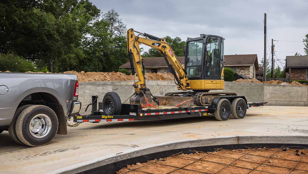 a truck is towing a 14tl tilt trailer with a cat excavator on it