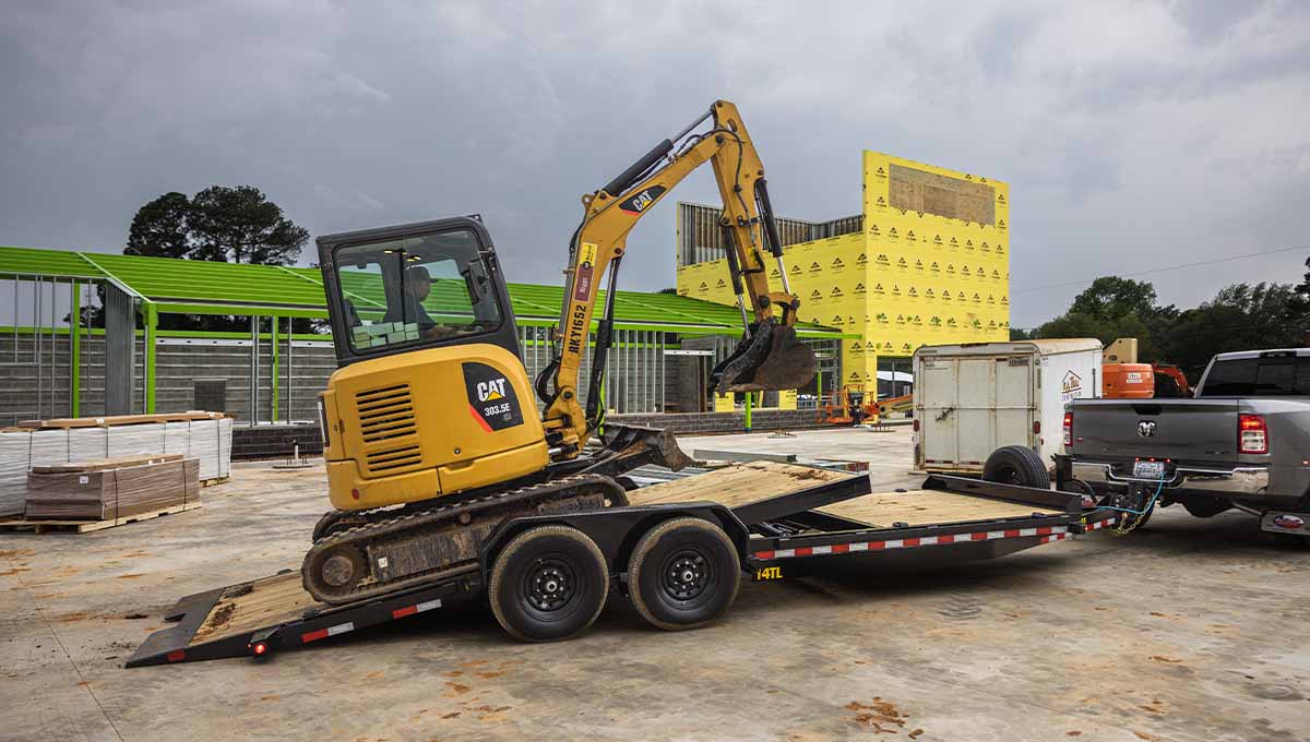 a cat excavator is being towed by a 14TL low profile tilt trailer