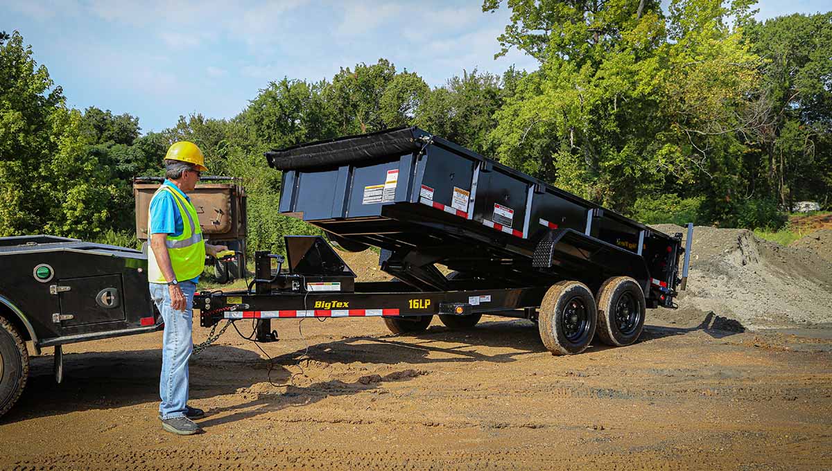 a man standing next to a 16lp dump trailer that says big tex