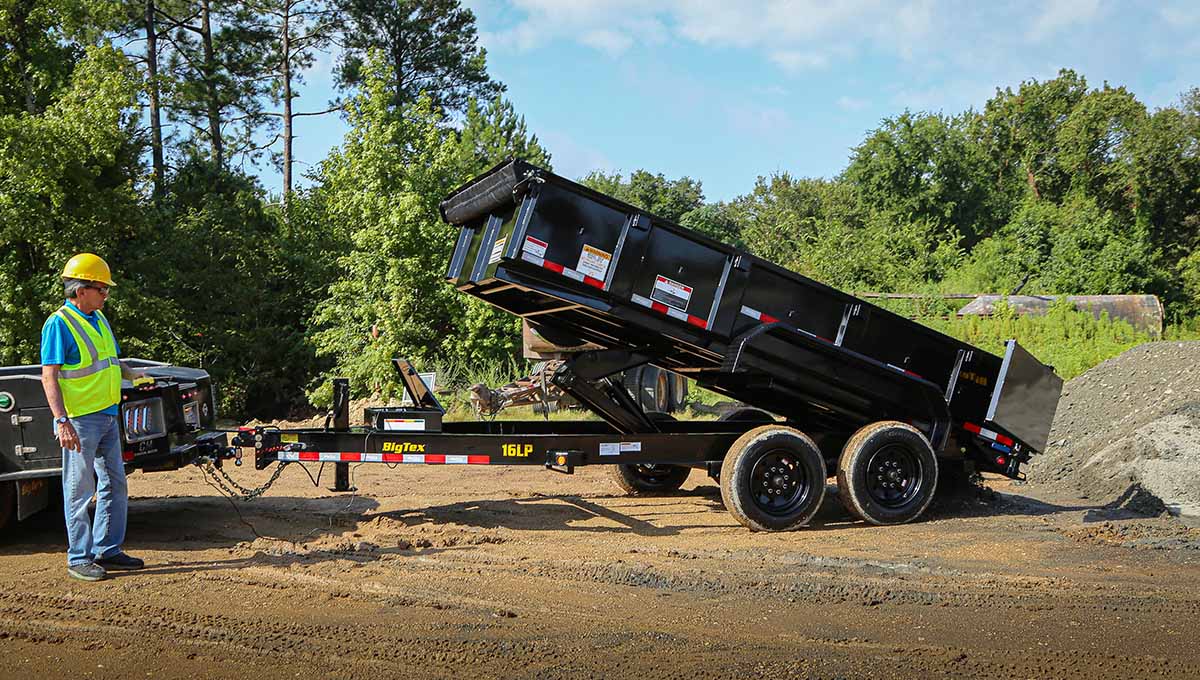 a man in a hard hat stands next to a 16lp commercial grade dump trailer