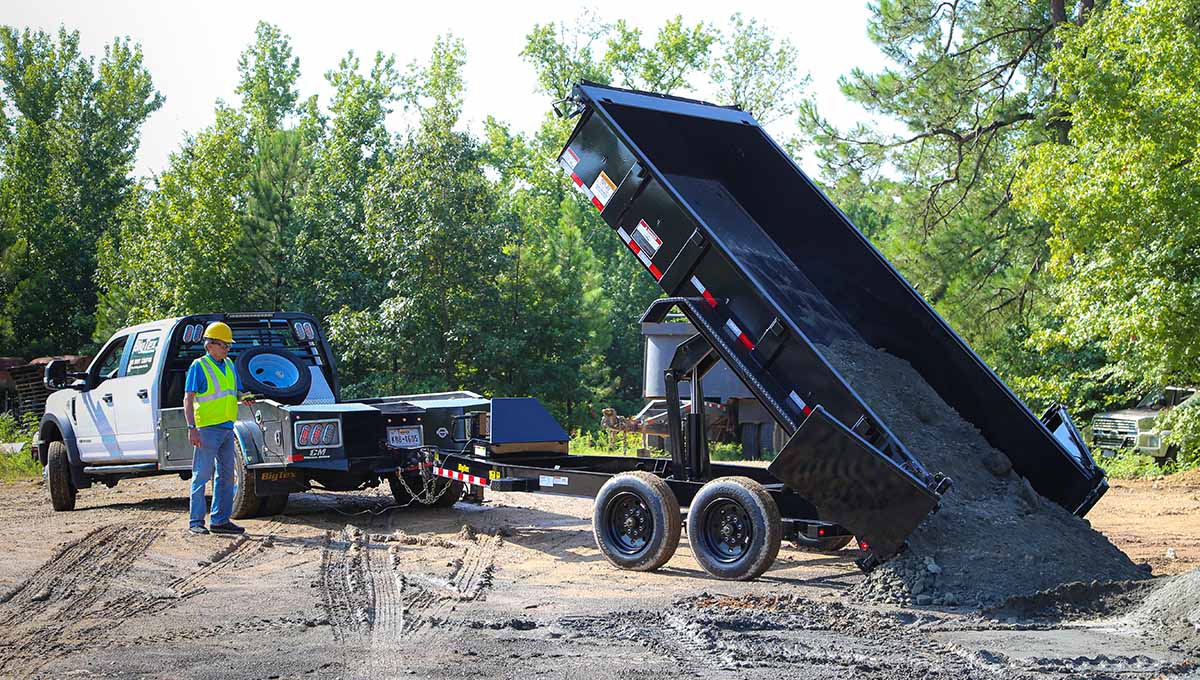 a man in a hard hat stands next to a 16lp commercial grade dump trailer