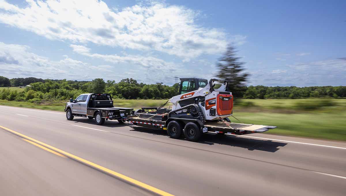 a bobcat tractor is being towed by a 16tl tilt trailer