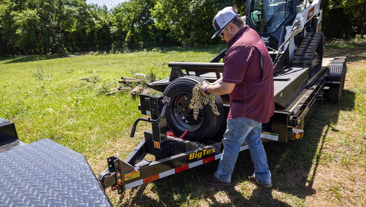 a man is working on a 16tl low profile tilt big tex trailer