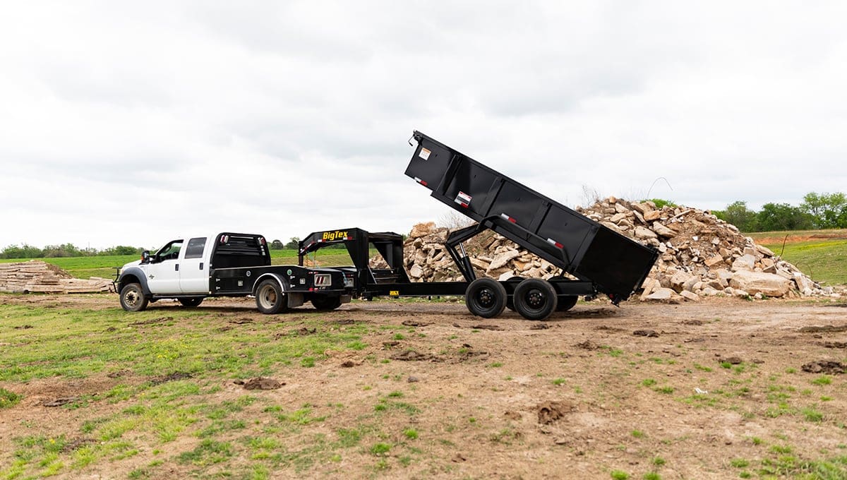 a dumpster is being towed by a truck with a bed that says ' utility ' on it