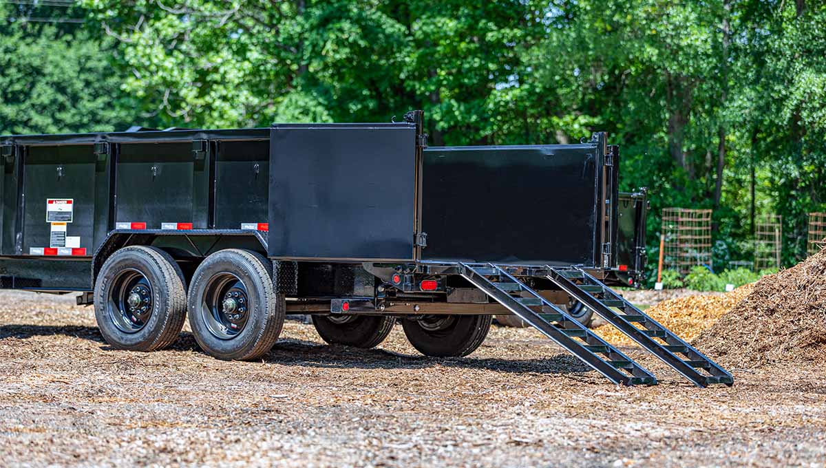 a black 20lp commercial grade dump trailer is parked in a dirt field