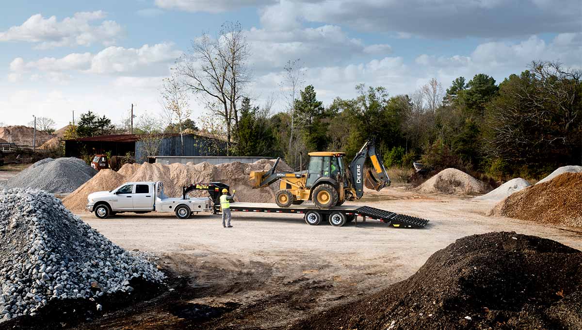 a deere tractor is being towed by a white truck with a 3xgn gooseneck trailer