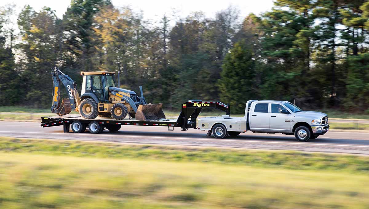 a tractor is being towed by a 3xgn big tex gooseneck trailer