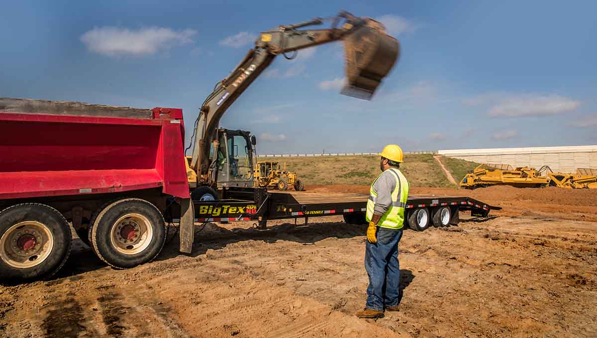 a man stands in front of a 4xph big tex dump truck