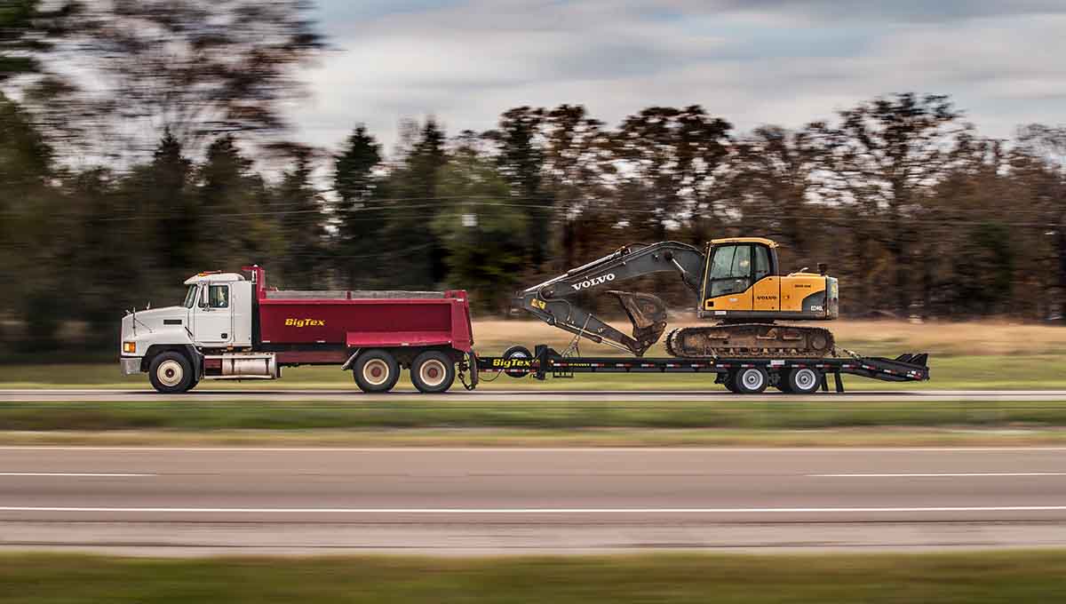 a volvo excavator is being towed by a dump truck