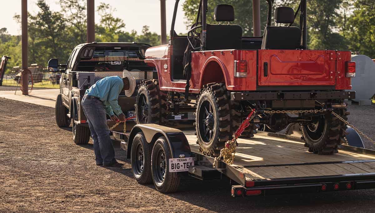 a red jeep is on a 70CH car hauler trailer with a big-tex license plate