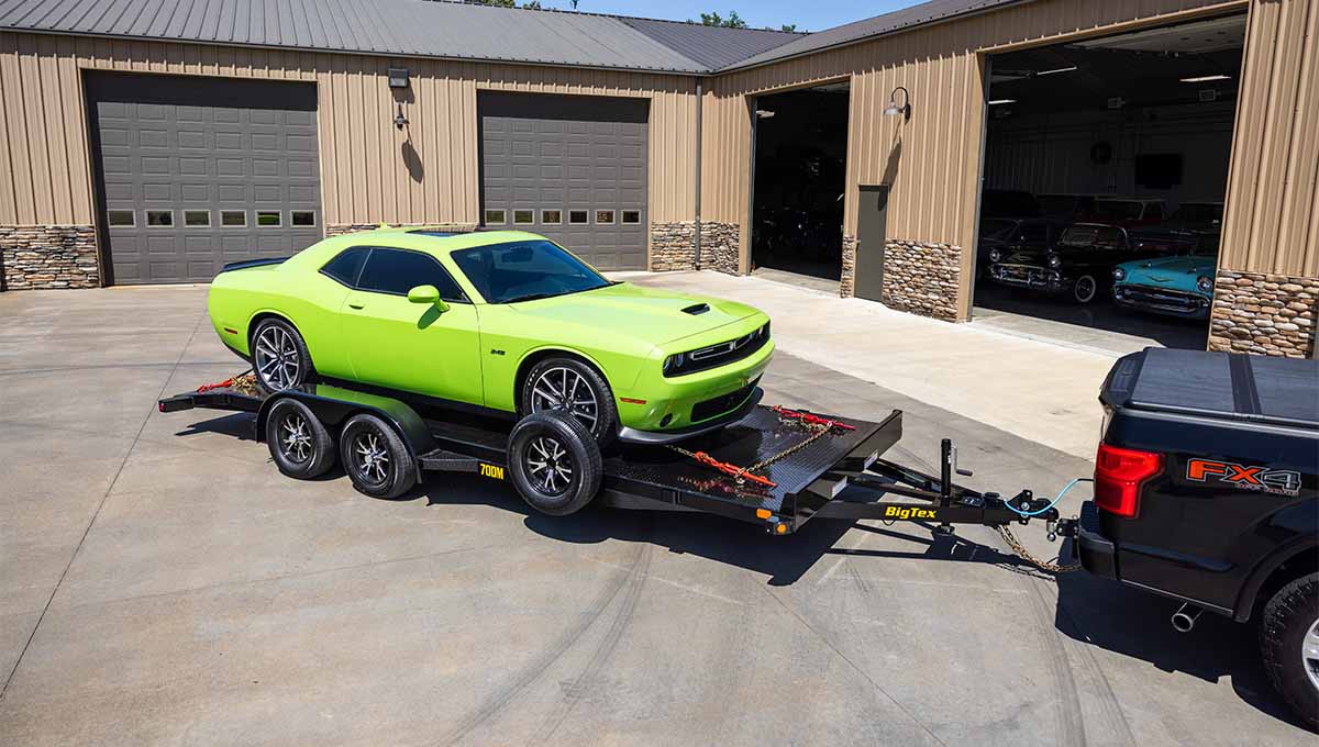 a yellow dodge challenger is being towed by a 70dm car hauler