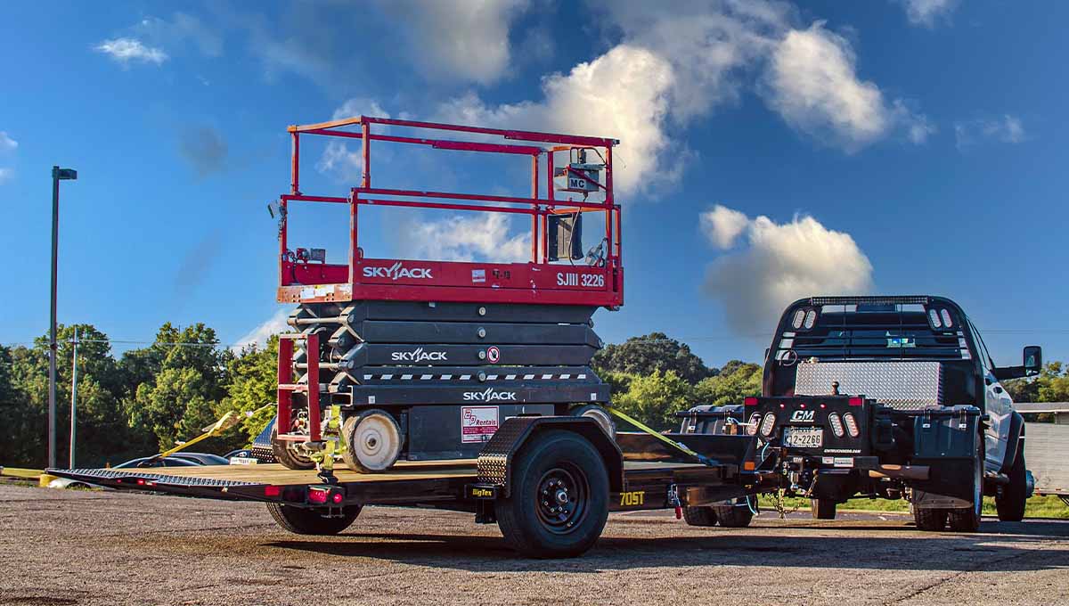 a skyjack scissor lift is on a 70st tilt trailer attached to a truck