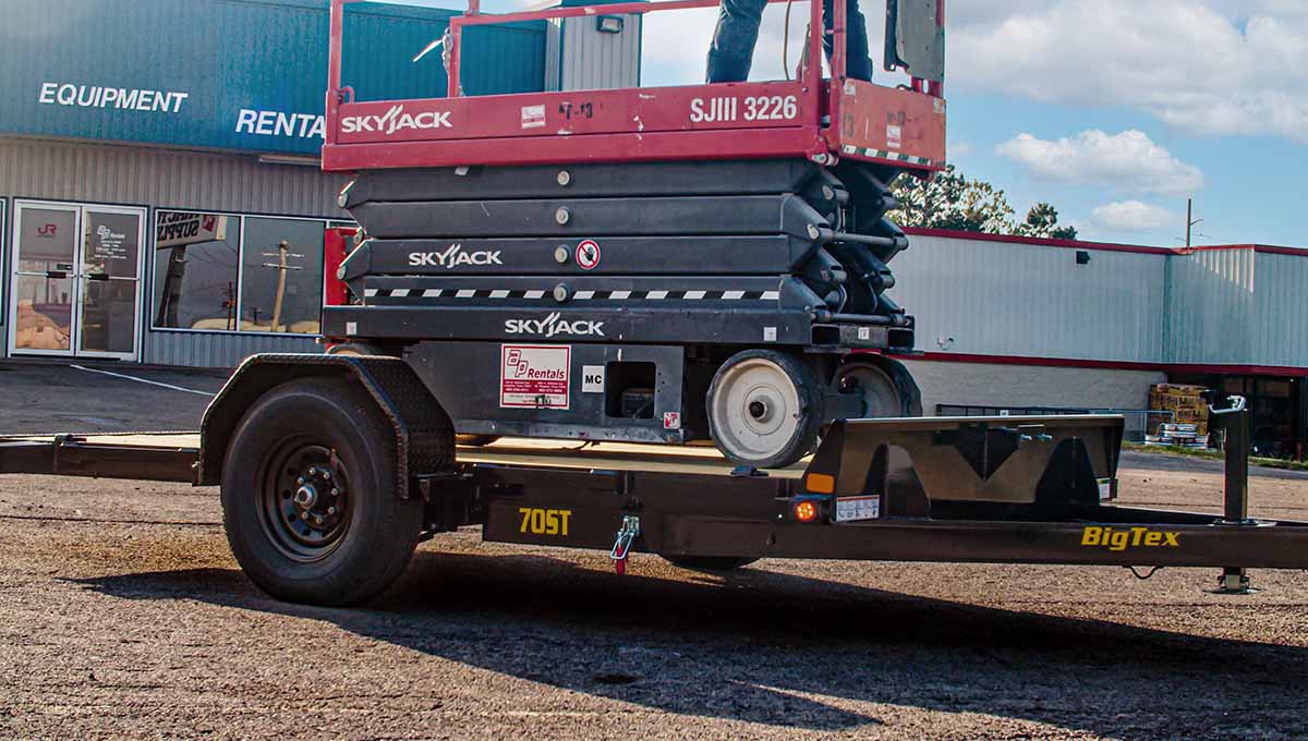 a red and black skyjack scissor lift on a 70st tilt trailer