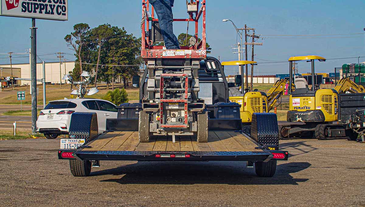 a komatsu tractor is parked in front of a 70st tilt trailer