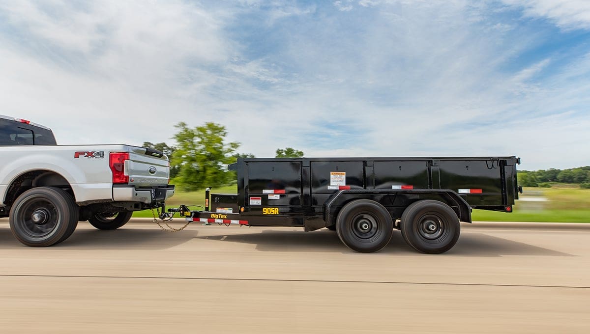 a white ford truck is pulling a 90sr dump trailer