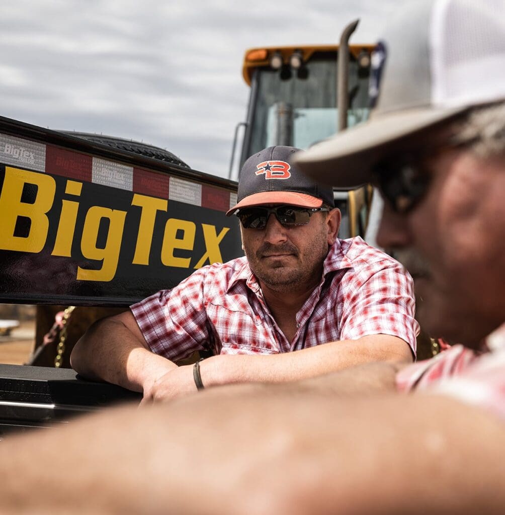 two men sit in front of a big tex sign