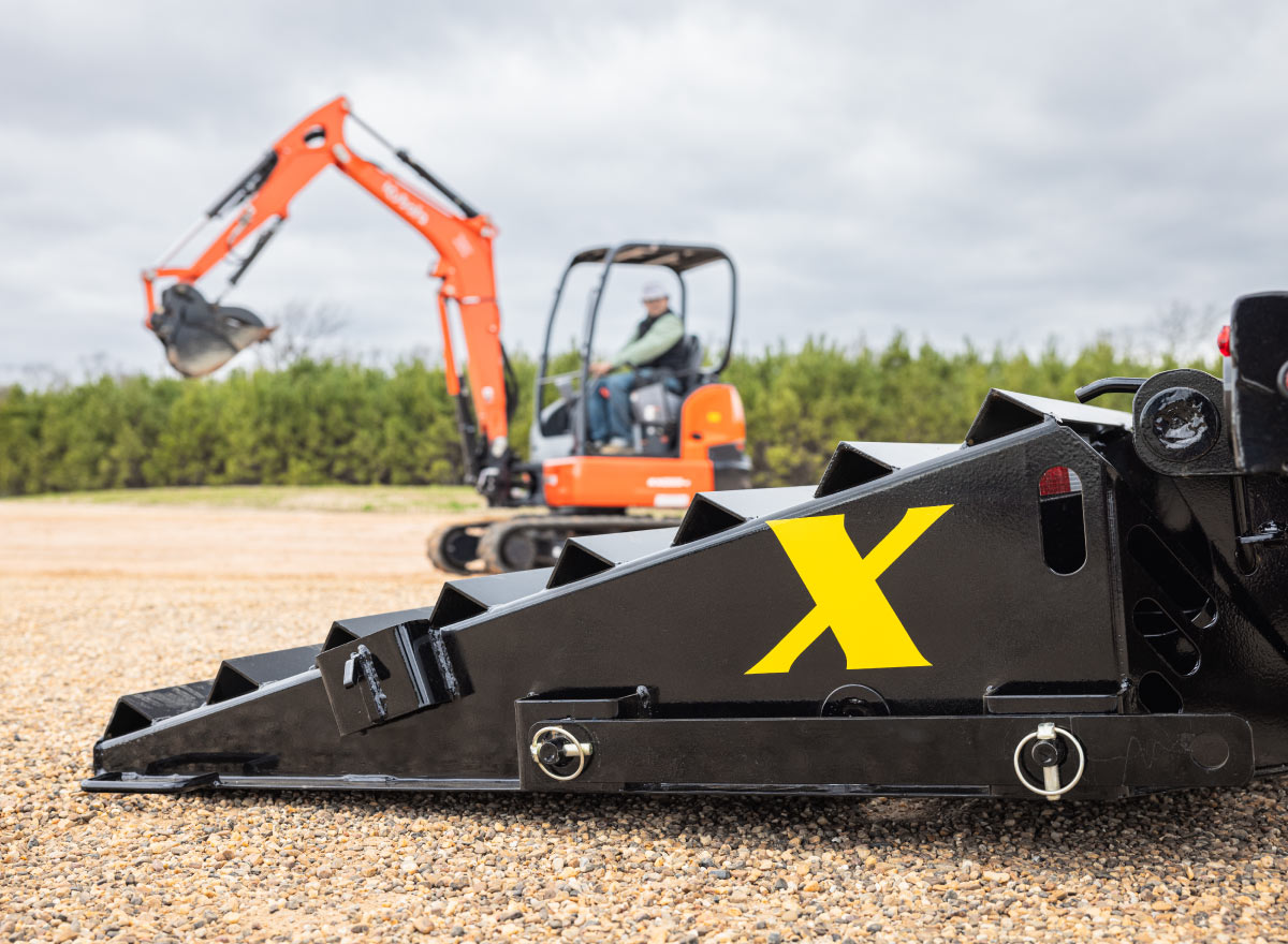 an orange excavator is parked behind a black ramp with a yellow x on it